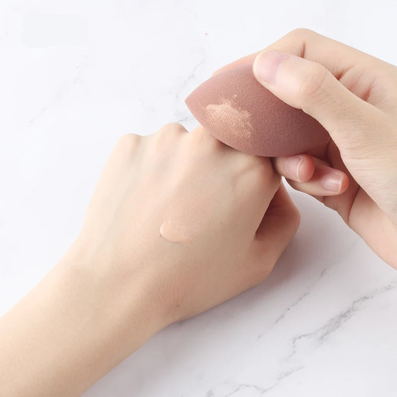 Cosmetic sponge held by a hand on a white marble background with 'IMAGIC' branding.